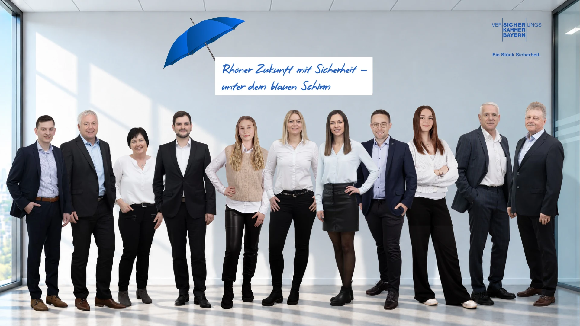 Das Team des Versicherungsbüros Baumbach im Büro unter dem blauen Schirm